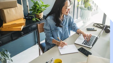 Woman working at a desk with a laptop and packages around her