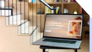 Laptop on a desk showing Squarespace's homepage with the text 'The leader in website design'.