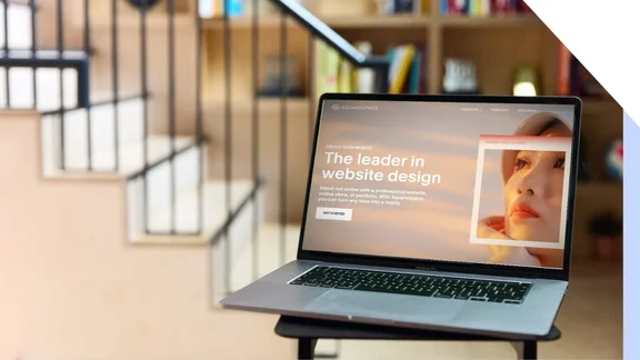 Laptop on a desk showing Squarespace's homepage with the text 'The leader in website design'.