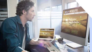 Man works at two screens building a website