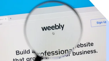 A magnifying glass hovers over a screen showing the Weebly logo