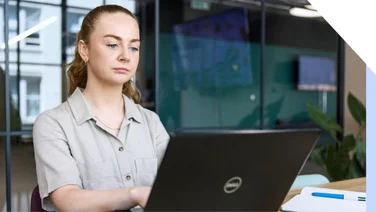 A focused professional woman works intently on her laptop in her business' office