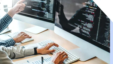 Screenshot of two hands typing on desktops with code on them