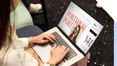 Woman working on her portfolio website design on her laptop in a casual setting.