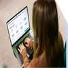 Woman using a laptop to complete an online purchase for a web builder with various prices displayed on her checkout screen