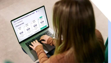 Woman using a laptop to complete an online purchase for a web builder with various prices displayed on her checkout screen
