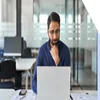 Man working at a desk looking at a laptop screen in an office