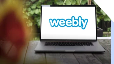 Laptop sits on a table outside displaying the Weebly logo