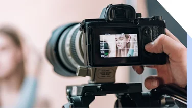Hand holding lens camrera with a person visible through the preview screen