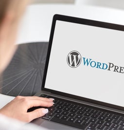 Woman looks at WordPress logo on her laptop