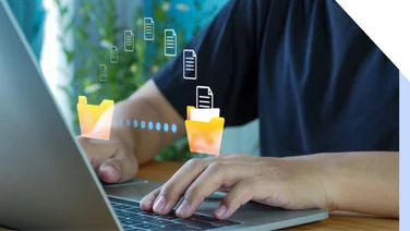 Person types on laptop with file graphics floating above their hands