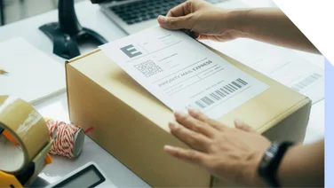 Person placing a shipping label onto a package