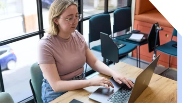 A focused professional woman working diligently on her laptop in a well-lit modern office setting