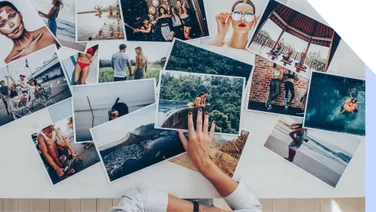 A hand sorting printed images on a table
