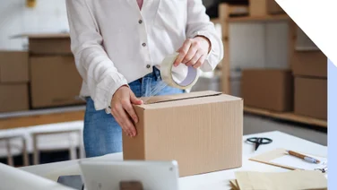 Photo of a woman packing up a parcel box with tape