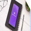 Cellphone shows the Hostinger logo, and sits upon a closed otebook next to glasses and a pen