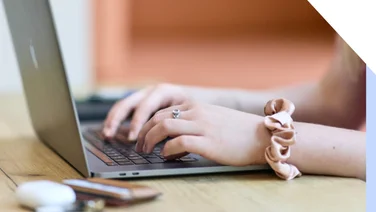 Close-up of a woman's hands typing on a laptop keyboard, showcasing productivity and technology use.