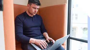 Man concentrates working and typing on his laptop in a modern office setting