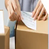 Person placing a shipping label on a package