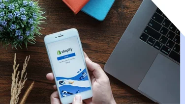 Hand holds cell phone with Shopify app on the screen