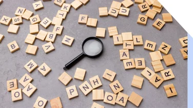 Magnifying glass surrounded by scrabble tiles