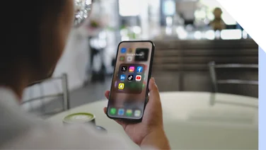 man looking at iPhone folder with seven social media apps inside