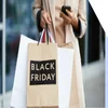Person holds phone in one hand and bags saying Black Friday in the other
