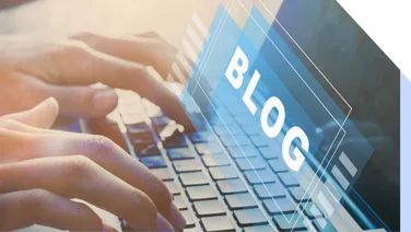 Laptop screen shows the word "Blog" while hands type on keypad