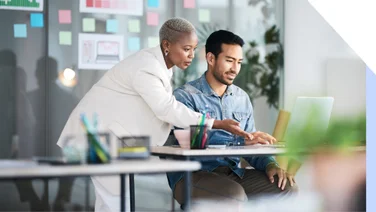 Woman showing a man how to do something on a laptop