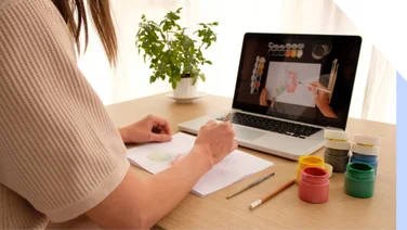 Woman does art in front of art website on laptop