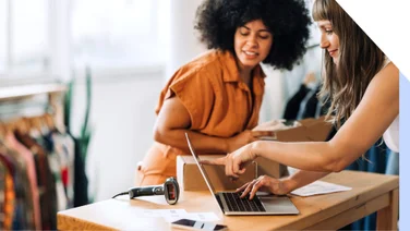 Two business owners look at their website on a laptop