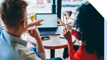 Two people pointing at a laptop
