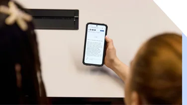 Over the shoulder view of two people looking at a smartphone displaying an article, sharing an interesting topic together.