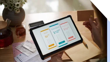 Tablet showing three subscription options with a person ready to pay holding the tablet
