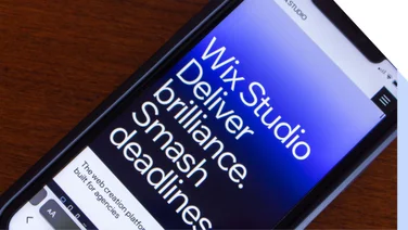 Screenshot of a mobile phone with Wix Studio's tagline on it "Deliver brilliance. Smash Deadlines".