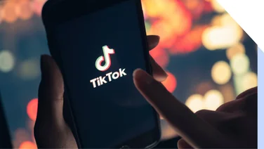 Hands holding a mobile device showing the TikTok logo on screen
