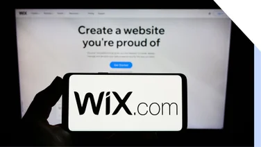 Photo of a mobile phone with the Wix logo in front of a laptop on the Wix website