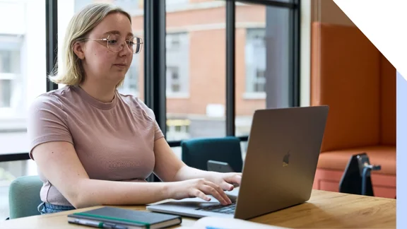 A focused professional woman working diligently on a laptop in an office setting