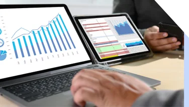 Photo of a laptop and a tablet with graph data on the screen