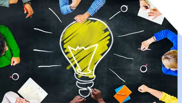 Lightbulb drawn on a chalkboard table with people gathered around it