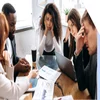 Group of people looking stressed around a work table as if trying to solve a problem
