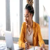 Woman working on a table and smiling at her laptop