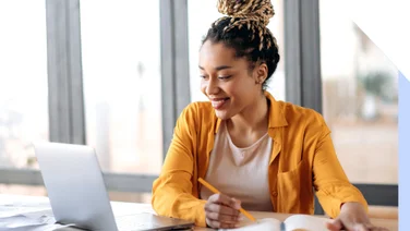 Woman working on a table and smiling at her laptop
