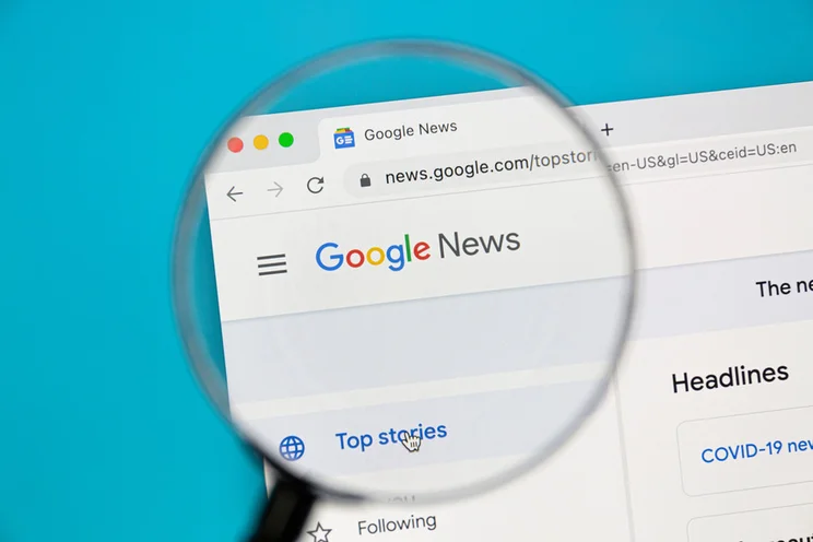A magnifying glass zooming into the Google news webpage