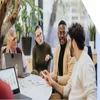 Group of office workers chatting around a table with laptops and paper in front of them