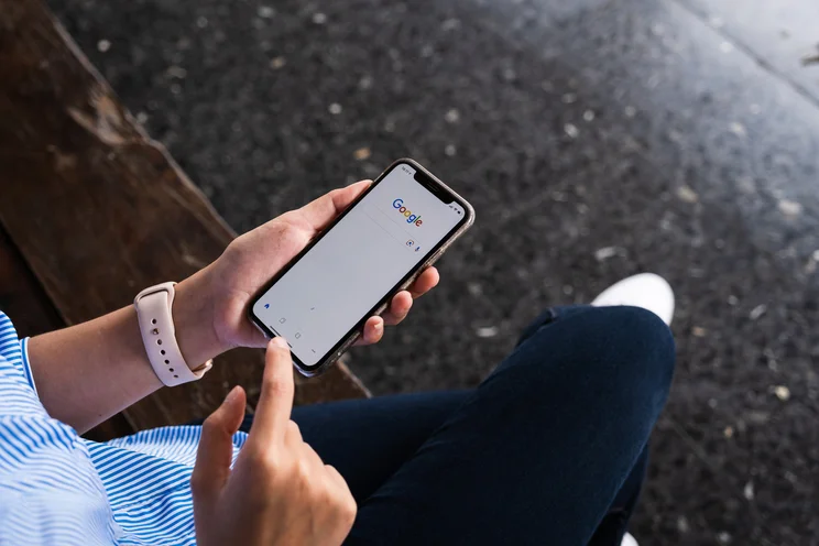 person using Google on phone while sat on a bench