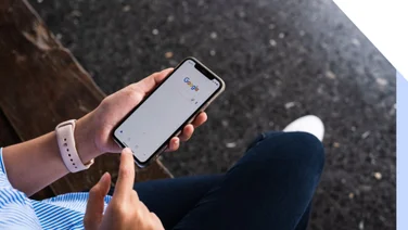 person using Google on phone while sat on a bench