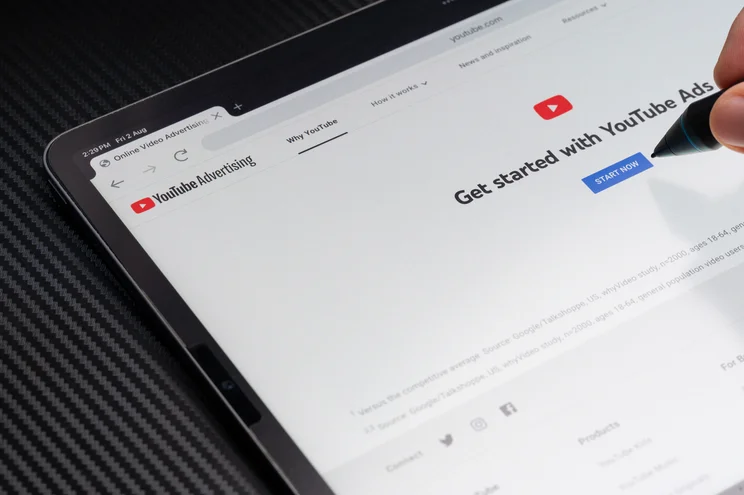 Person opening youtube app on a tablet and hovering a pencil over youtube icon