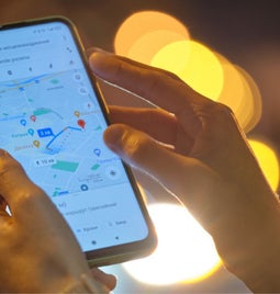 Person holding a mobile device showing Google Maps on the screen
