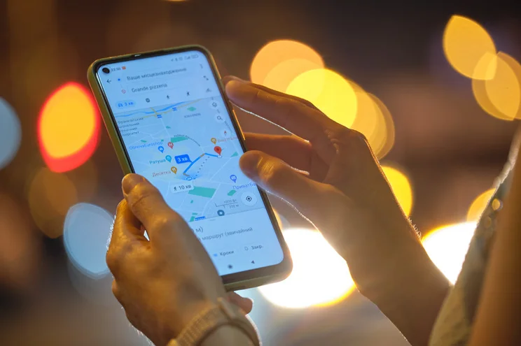Person holding a mobile device showing Google Maps on the screen